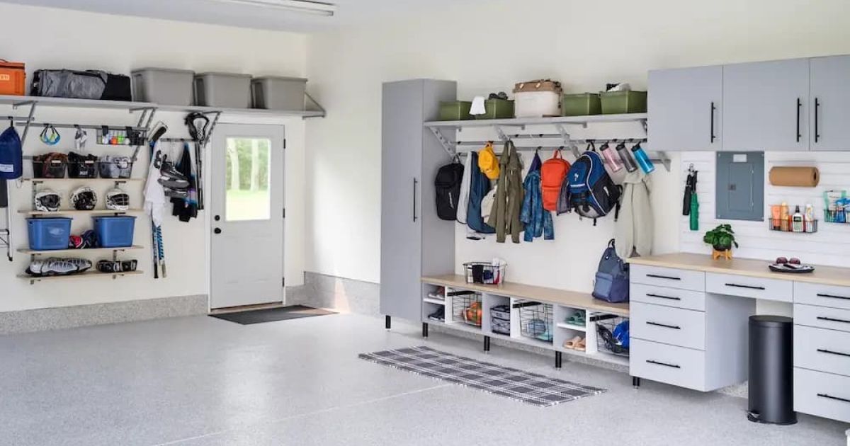 Bright garage with wall-mounted storage, coats, shelves, tools, and a workbench beside a door.
