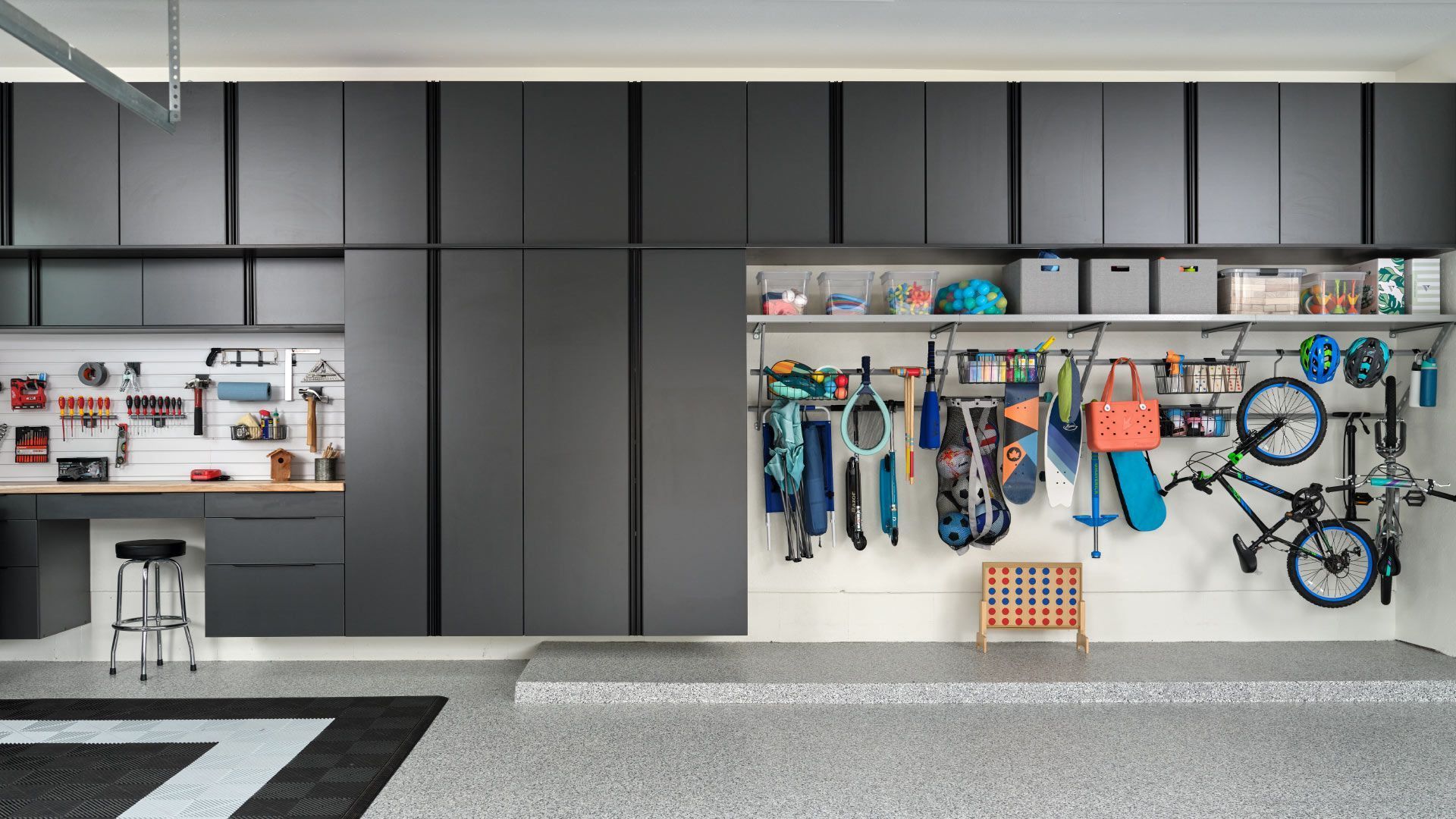 Modern garage with cabinets, workbench, and organized sports gear on wall hooks and shelves