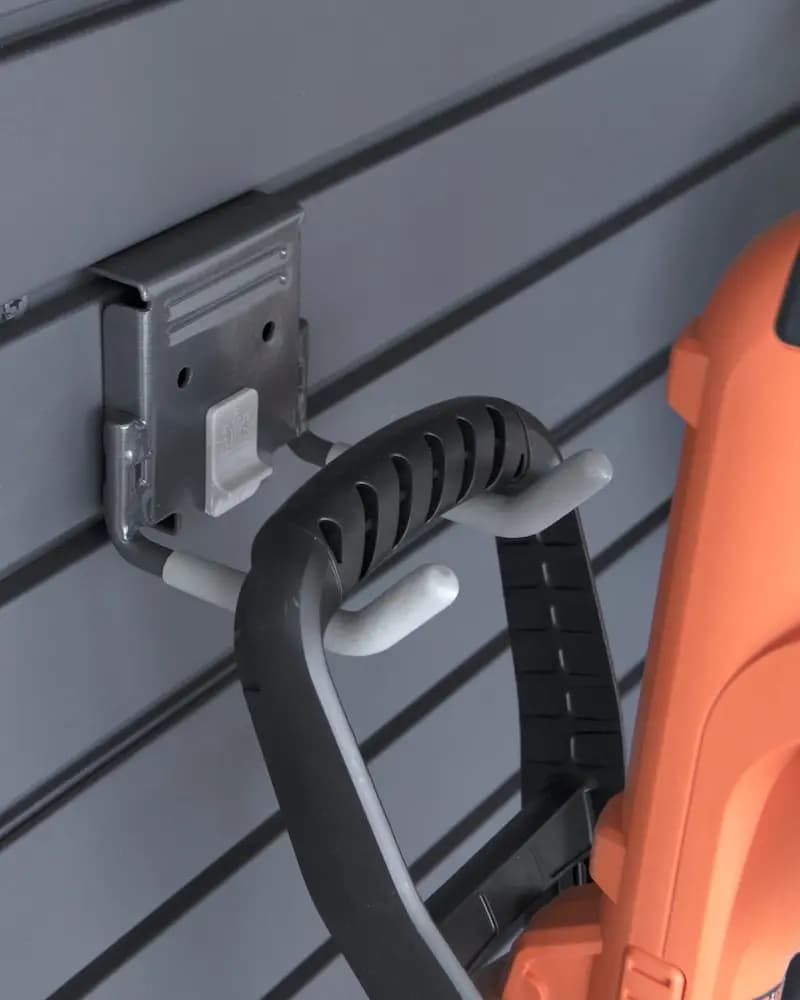 Wall-mounted metal charger beside a black handle and orange power tool on gray siding