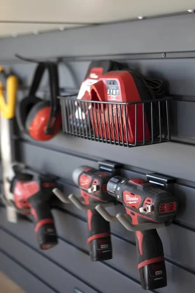 Red power tools and batteries organized on a gray garage wall rack