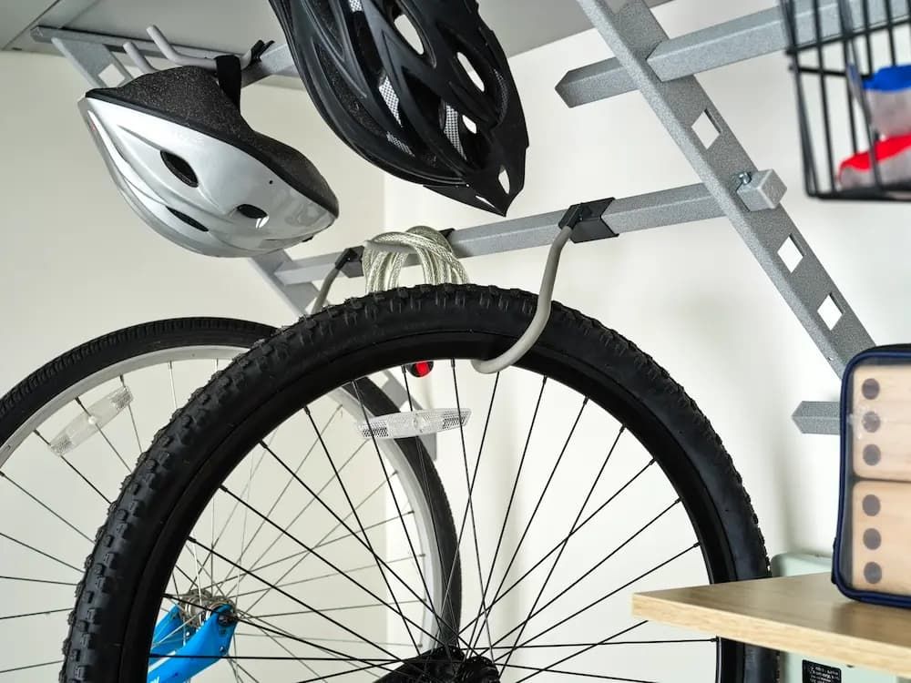 Bicycle stored on a wall rack with helmets hanging above in a garage