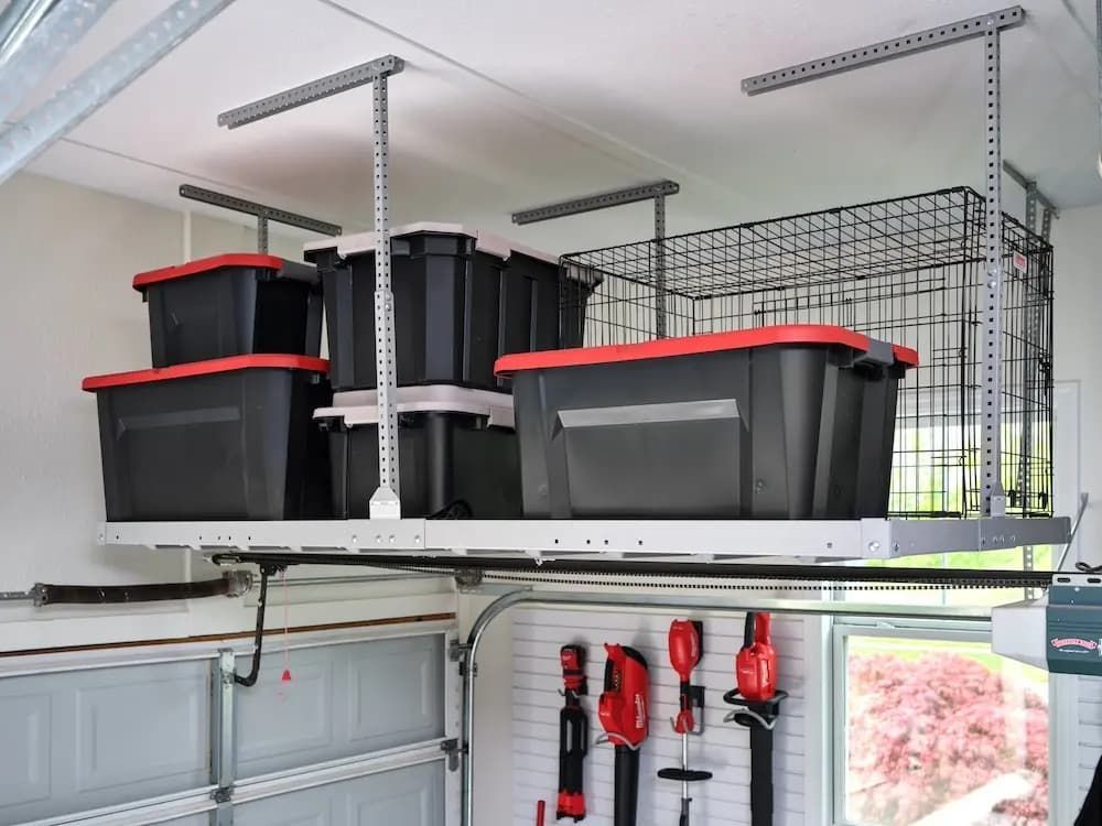 Garage storage shelves with black bins and red-handled tools mounted on the wall.