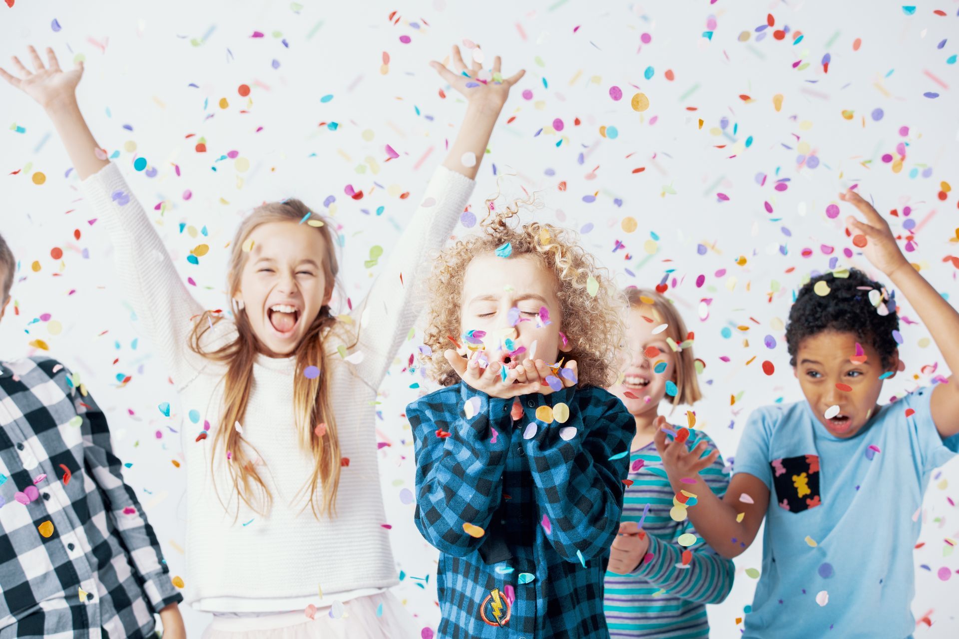 Children tossing colorful confetti into the air against a bright white backdrop. Children tossing colorful confetti into the air against a bright white backdrop.