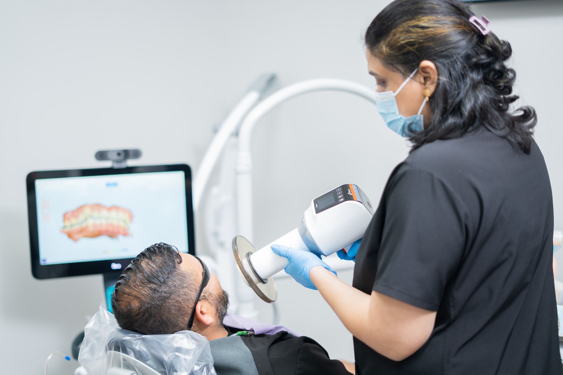 A dentist is examining a patient 's teeth in a dental office.