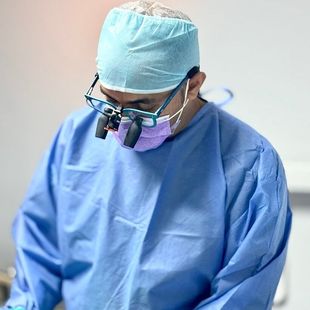Dr Keyur Patel in a dental surgery wearing a mask and magnifying glasses
