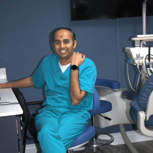 A woman in a lab coat is smiling in a dental office.