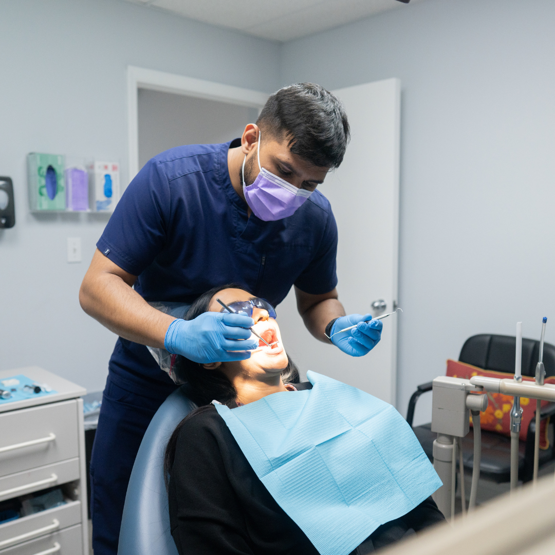 A female dentist is examining a man 's teeth in a dental office.