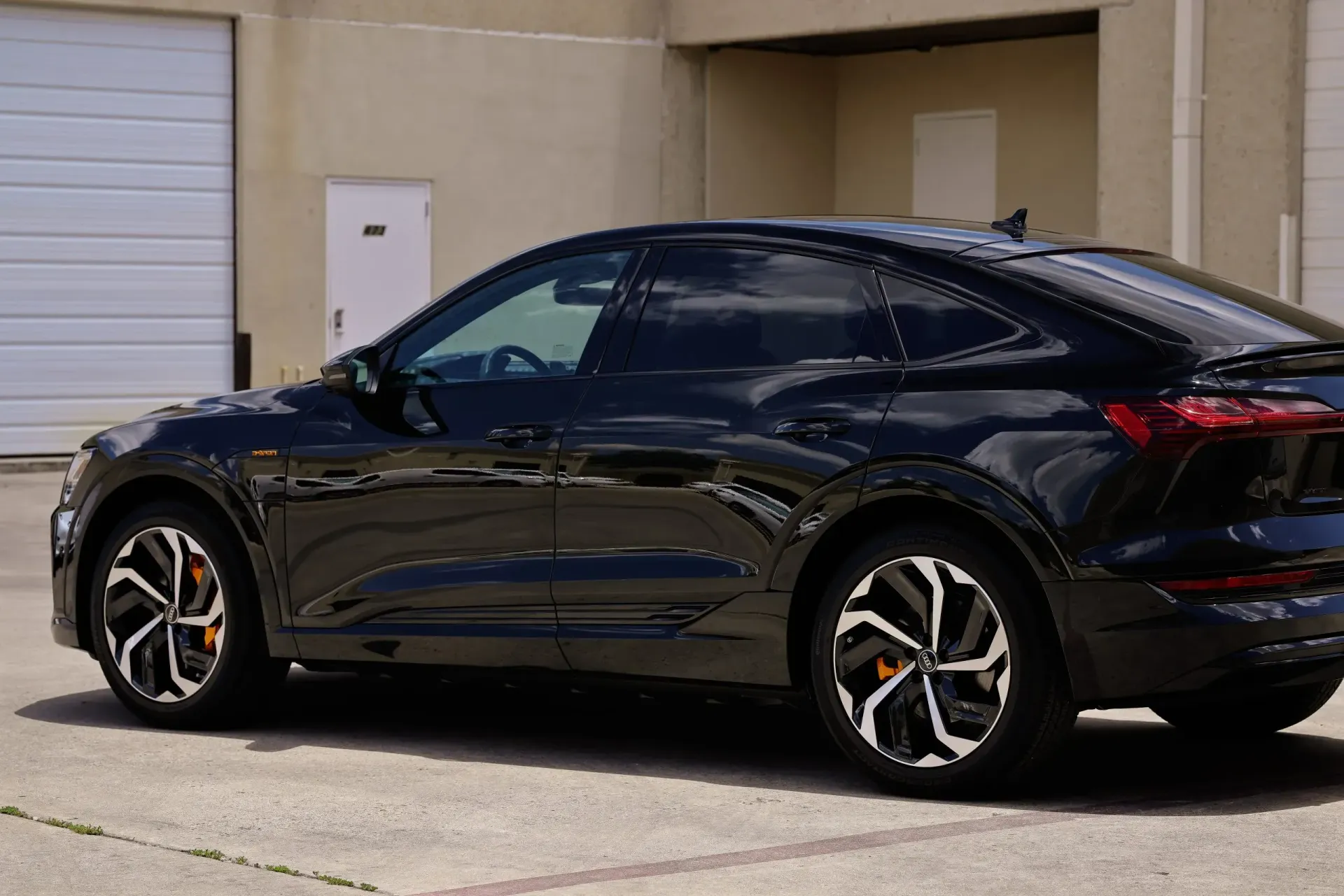 Black Audi SUV parked near a garage.