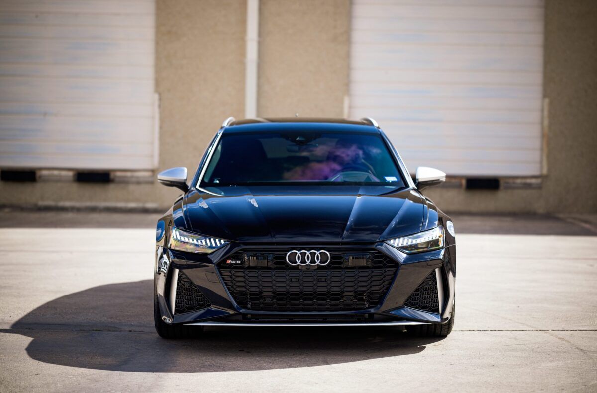 Black Audi RS6 Avant parked in front of garage doors.