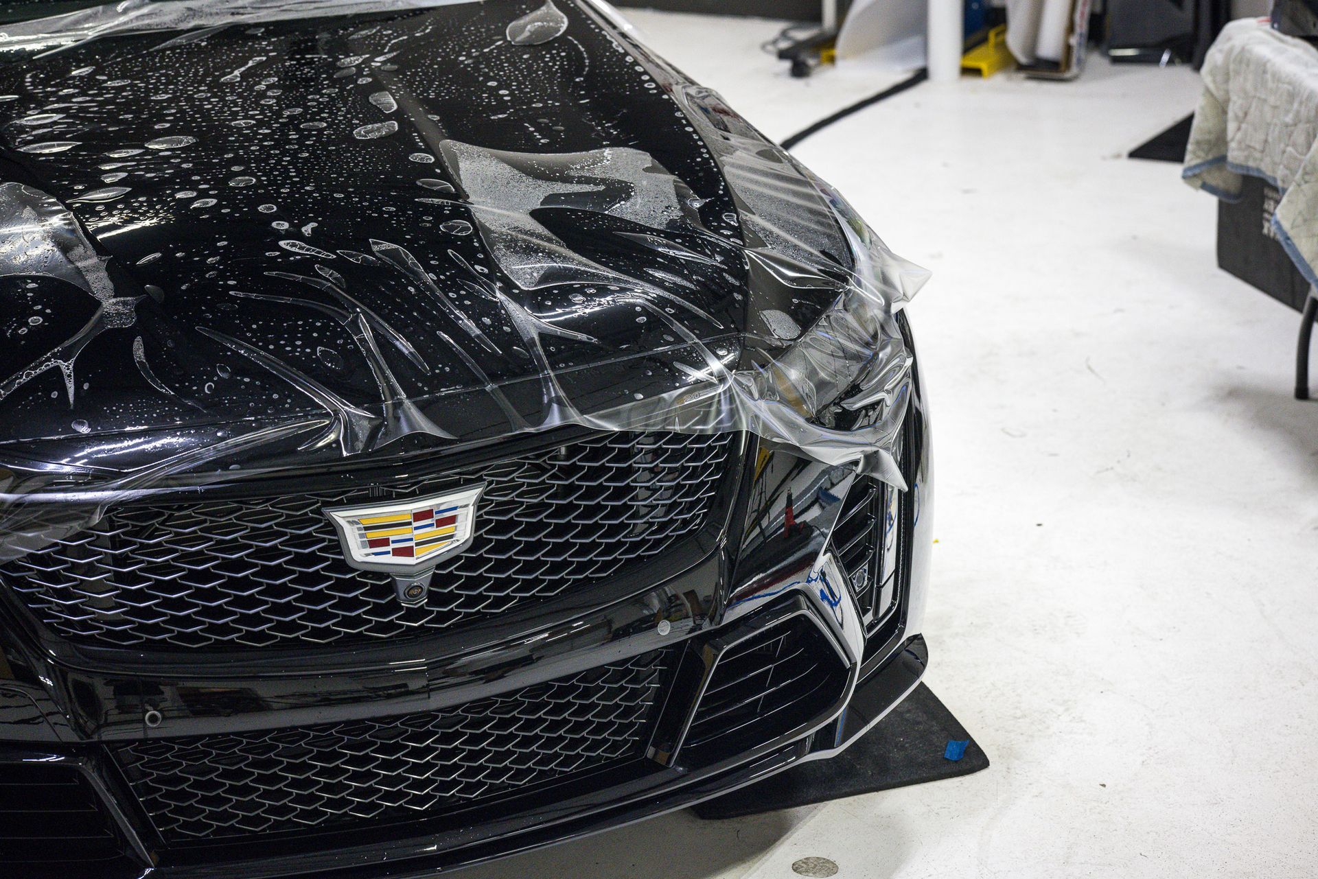 Black Cadillac with clear protective film on the front bumper.