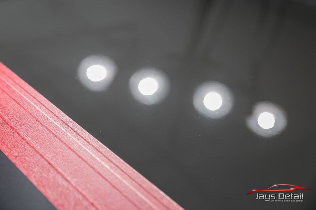 Red tape close-up with visible texture, angled against a blurred background with four bright lights.