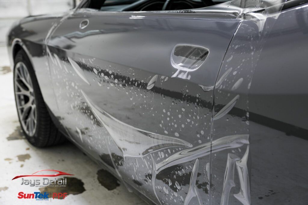 Gray car door with protective film applied, in a shop.