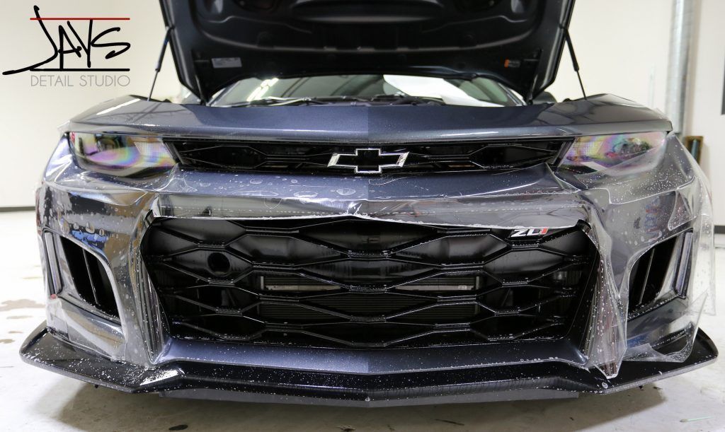 Dark gray Chevrolet Camaro with open hood, custom grill.