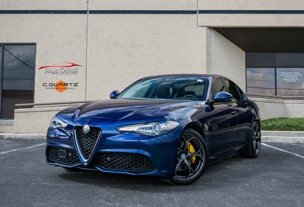 Blue Alfa Romeo Giulia parked in front of a building. Yellow brake calipers.