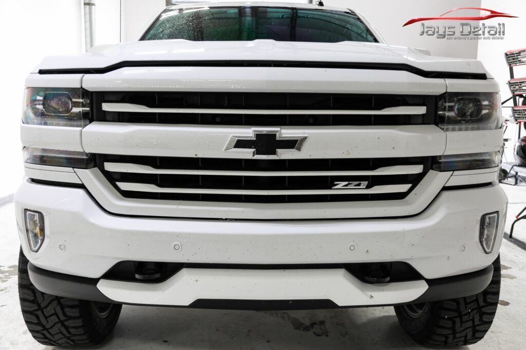 White Chevrolet Silverado truck, front view, black grill, tires.