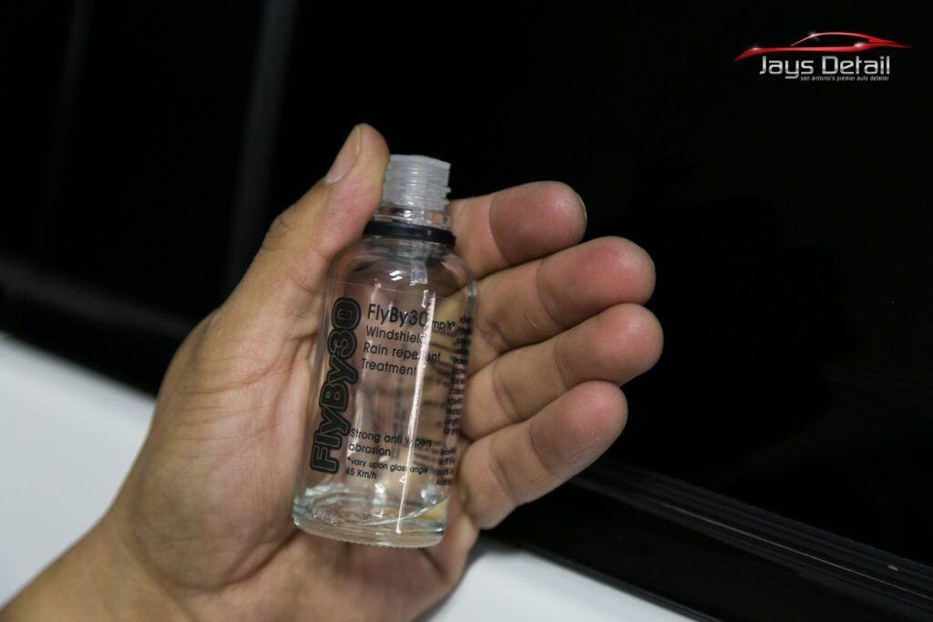 Hand holding a small, clear bottle labeled
