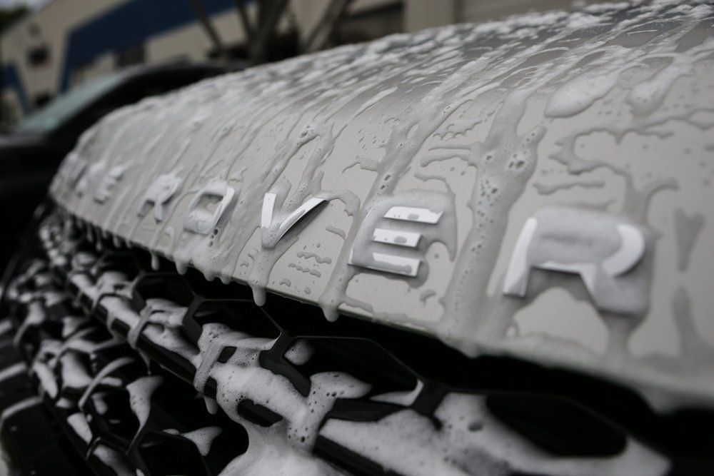 Silver Land Rover hood with soapy foam on it. The word 