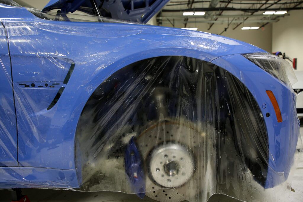 Blue car wheel well wrapped in protective film.