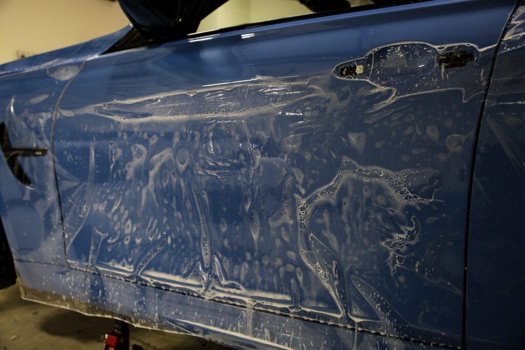 Blue car door covered in protective film.