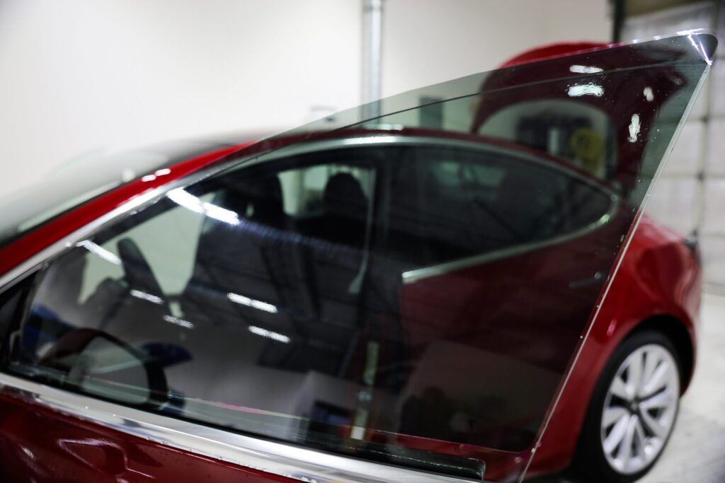 Red Tesla car with tinted windows in a garage.