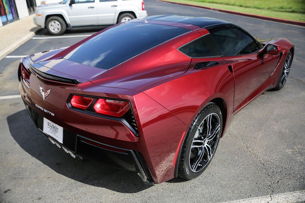 Red Chevrolet Corvette, black roof and wheels, parked on asphalt.
