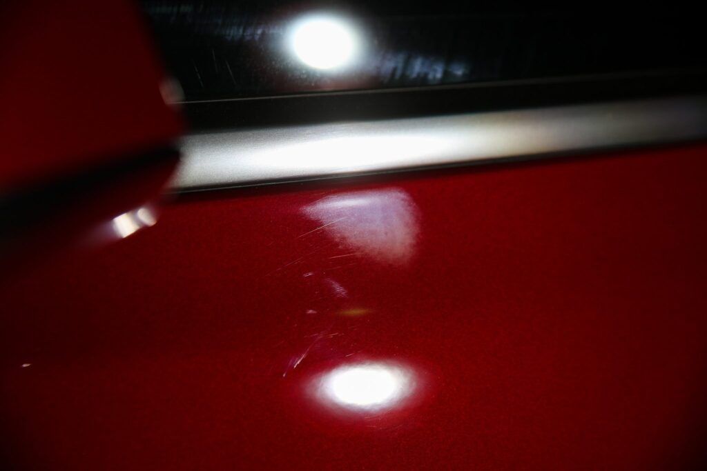 Red car paint with reflections and swirls.