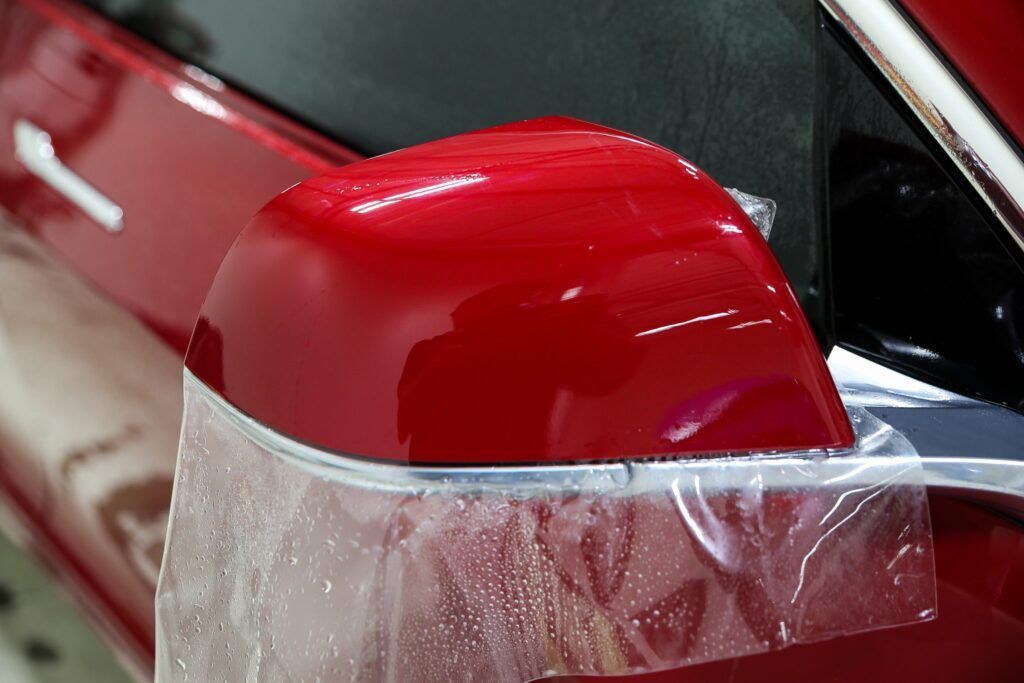 Red car side mirror with protective film.