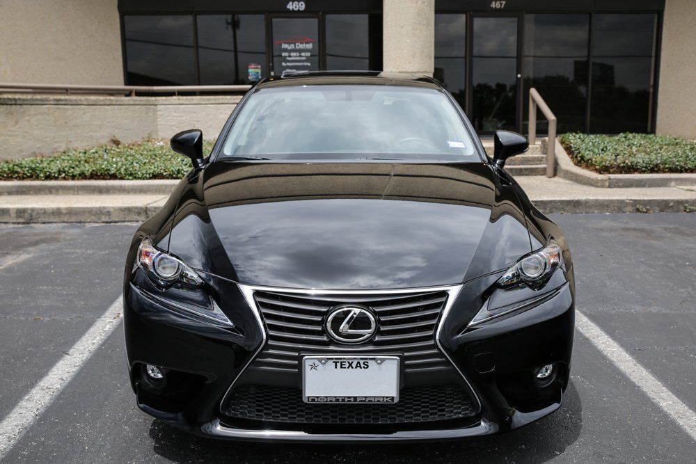 Black Lexus sedan parked in front of a building with a Texas license plate.
