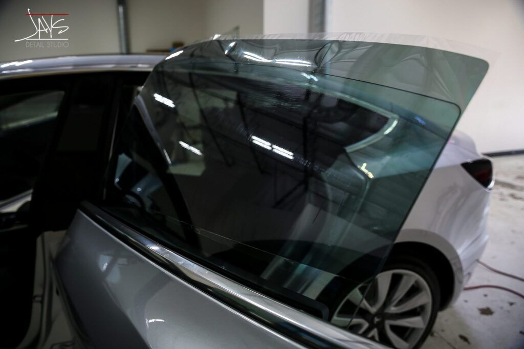 Silver car with tinted window film being applied.