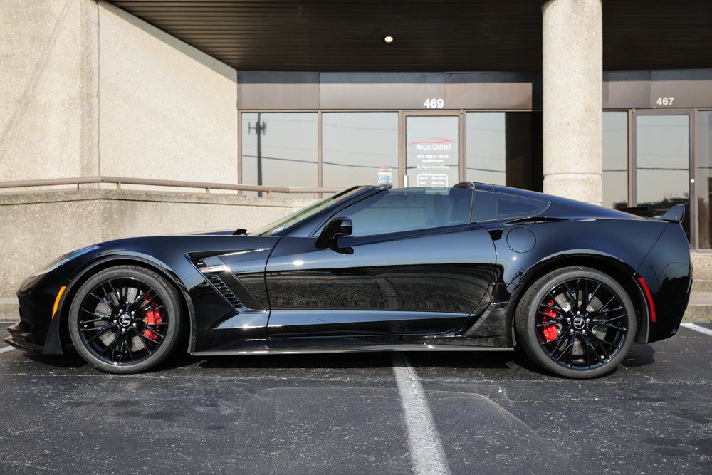 Black sports car parked outside a building, red brake calipers.