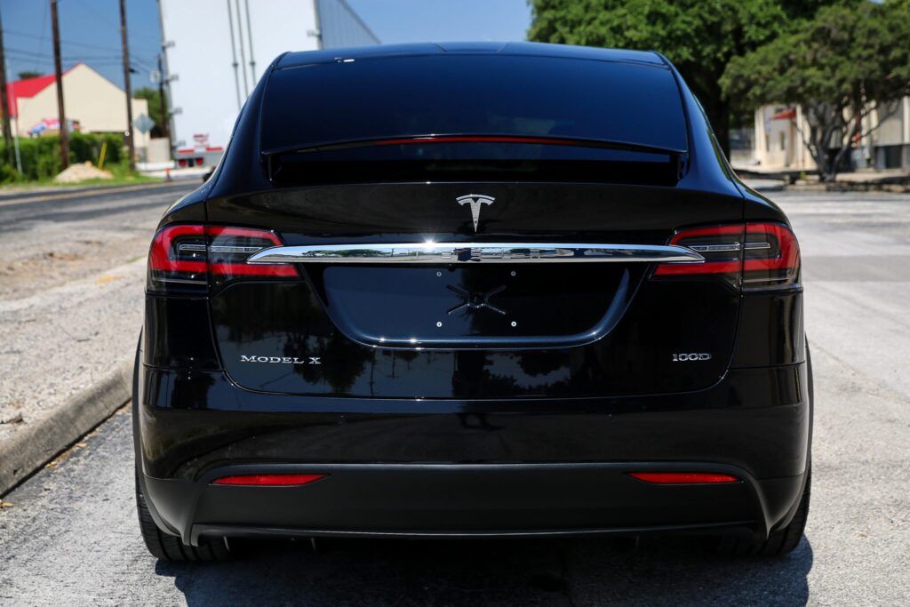 Black Tesla SUV from the rear, parked on a street.