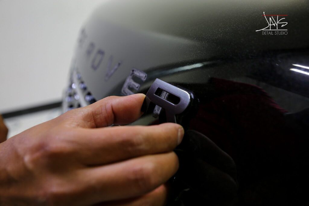 A person's hand placing a silver letter