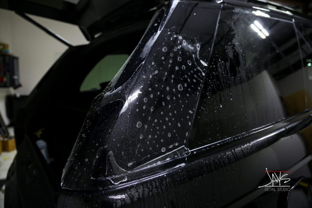 Car window with tinting film being applied, seen from the outside.