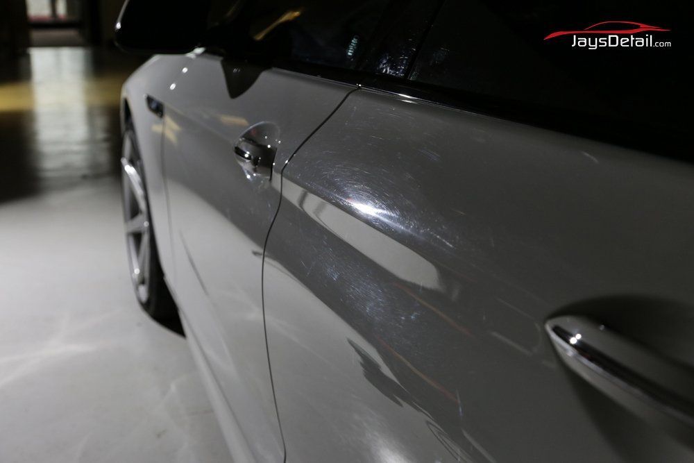 Gray car door with a chrome handle, reflecting light.