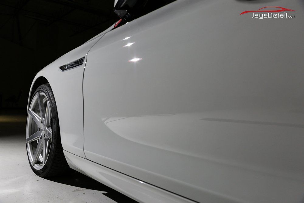 White car side profile with a silver wheel against a gray background.