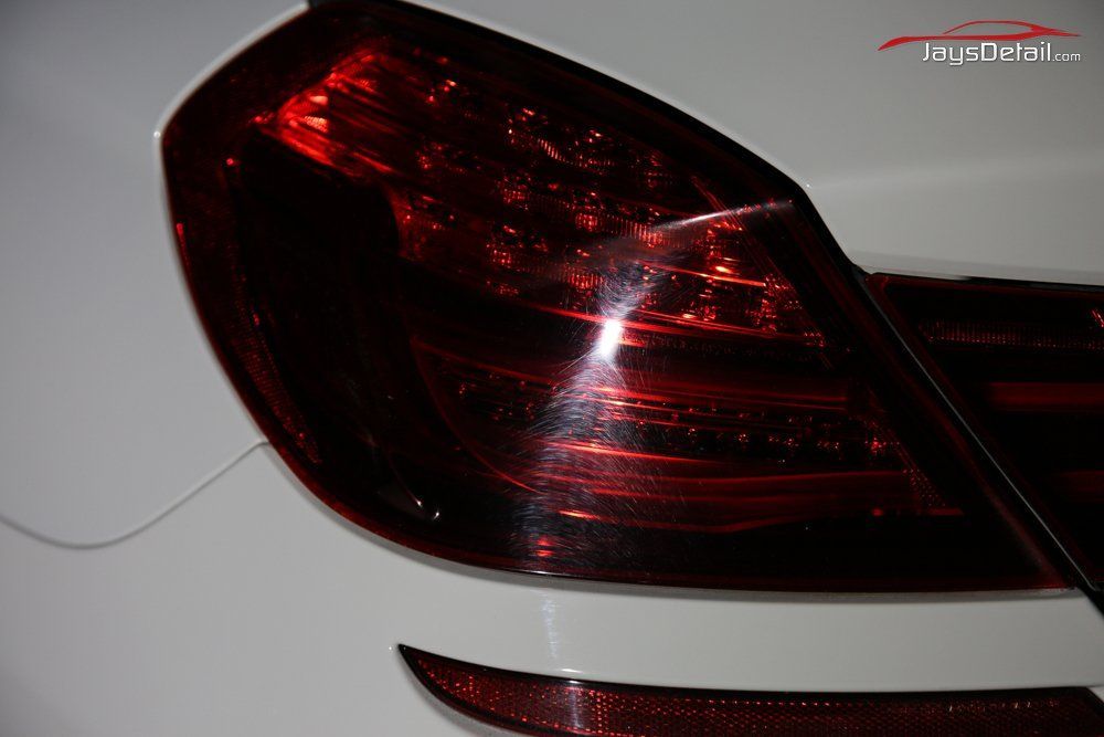 Red car taillight on white car body.