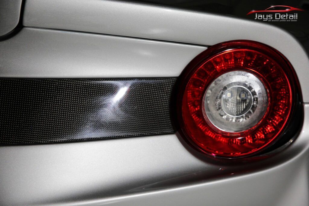 Silver car rear detail with a red tail light and carbon fiber accent.