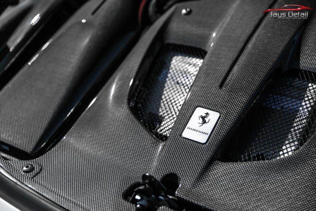 Carbon fiber engine compartment with a Ferrari logo.