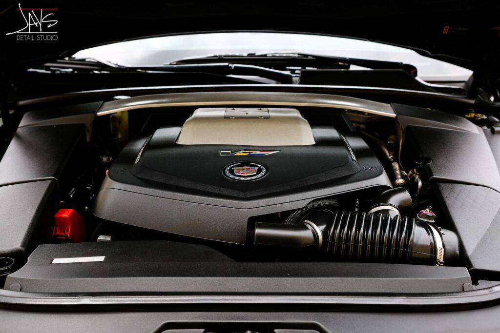 Engine bay of a black car, showing a silver and black engine.