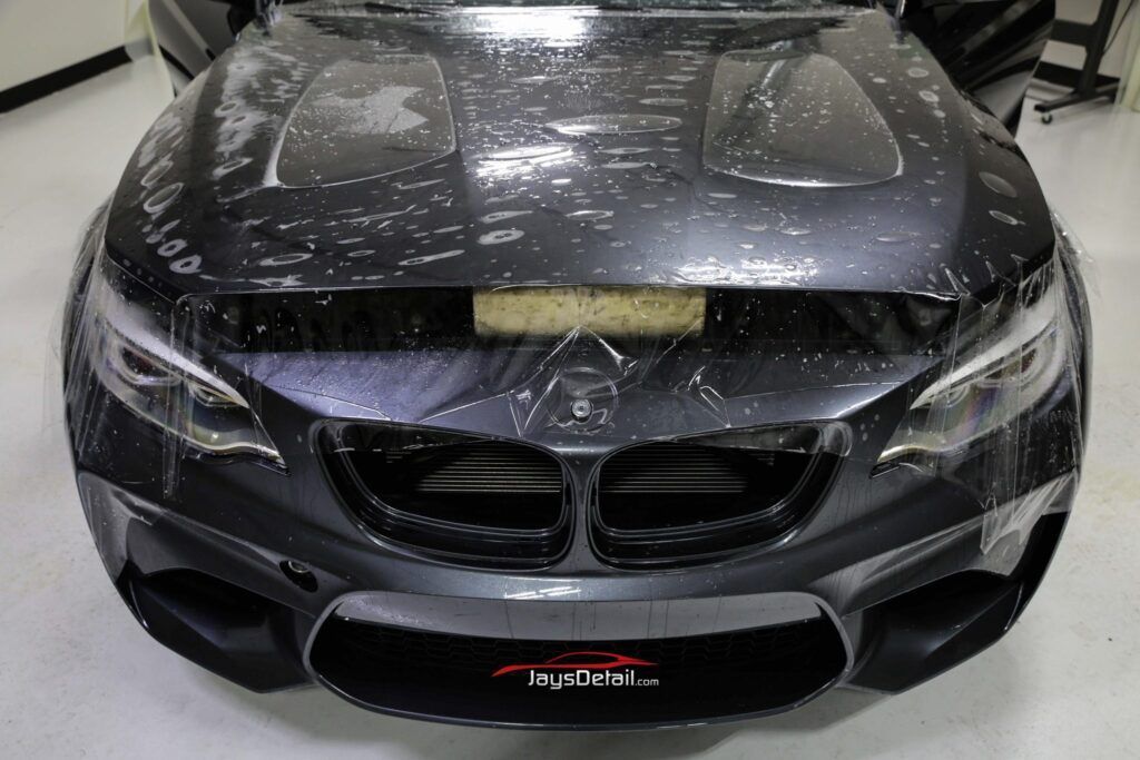 Dark gray BMW car being wrapped in protective film.