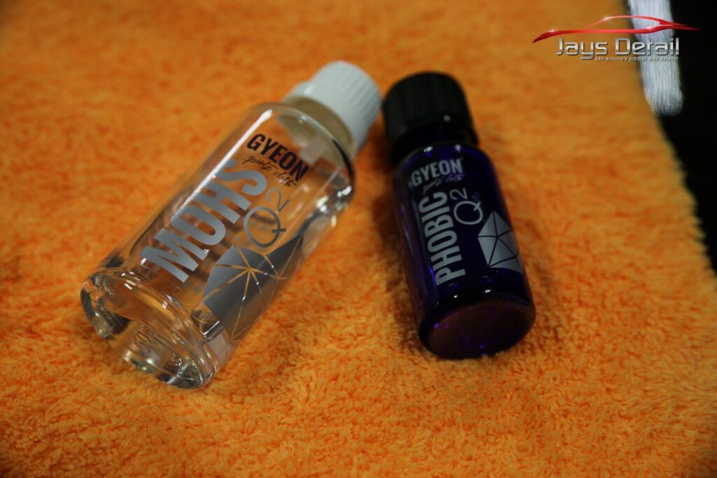 Two car care bottles, Gyeon MOIBUS and Phobic, on orange microfiber cloth.