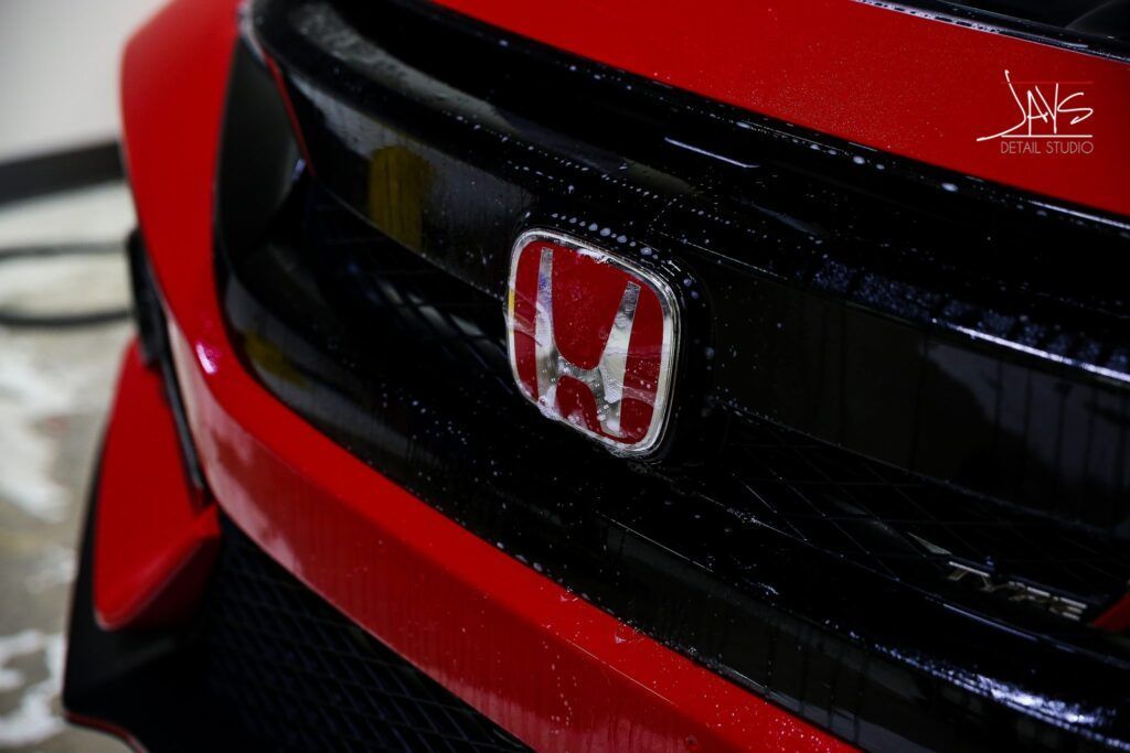 Red and black Honda car front grille with Honda emblem.