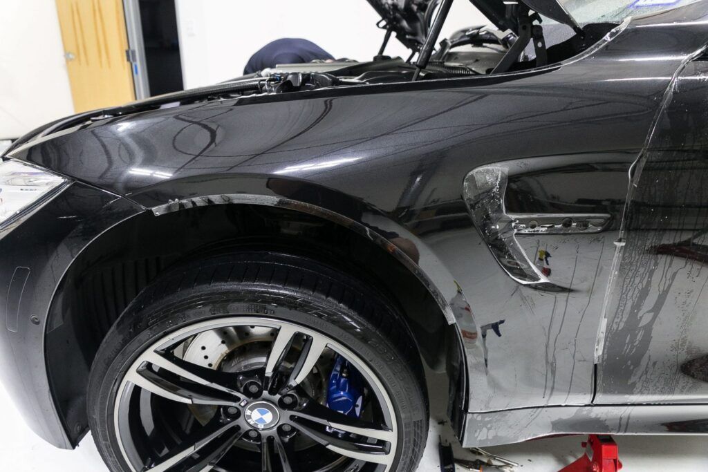 Black BMW car with an open hood, parked in a garage.