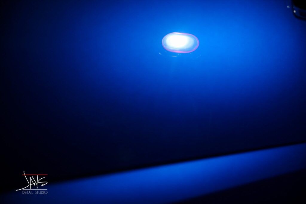 Blue light illuminating a dark surface; a small light source is at the top with a shadow on the bottom.