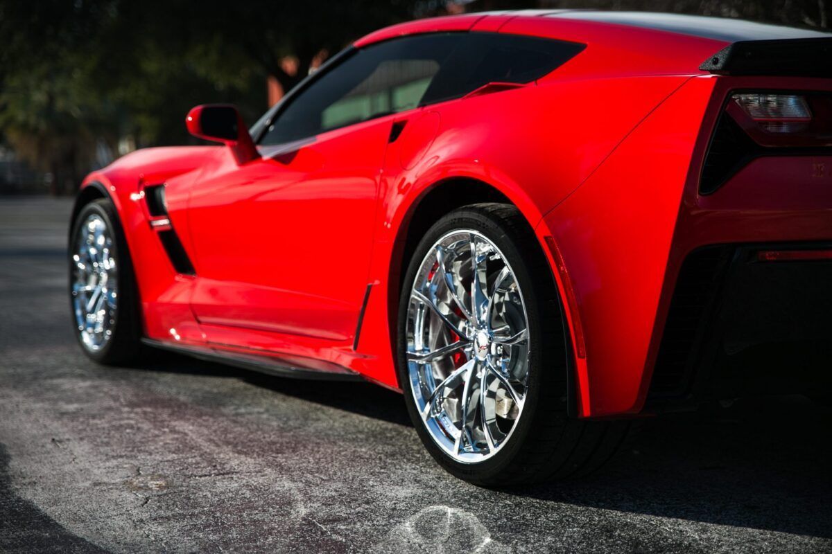 Red Corvette sports car with chrome wheels on asphalt.
