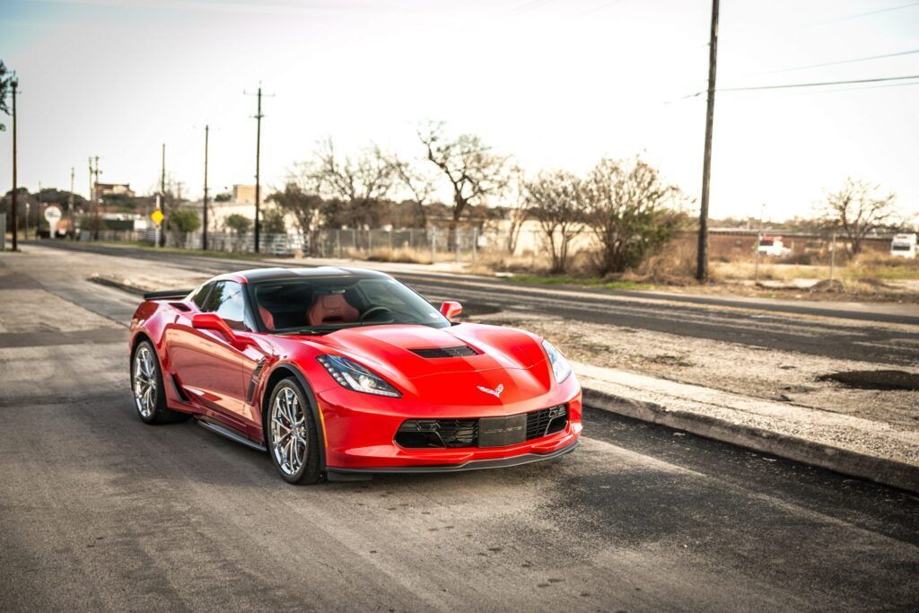 Red sports car driving down a rural road.