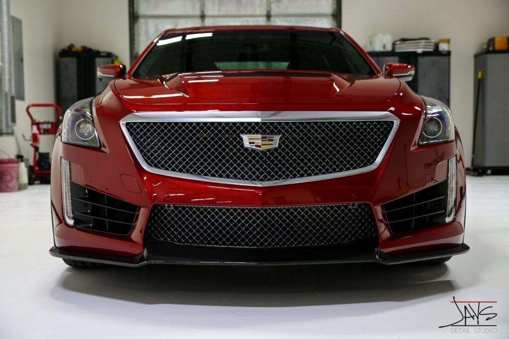Red Cadillac CTS-V sports car, front view, parked in a garage with a white floor.