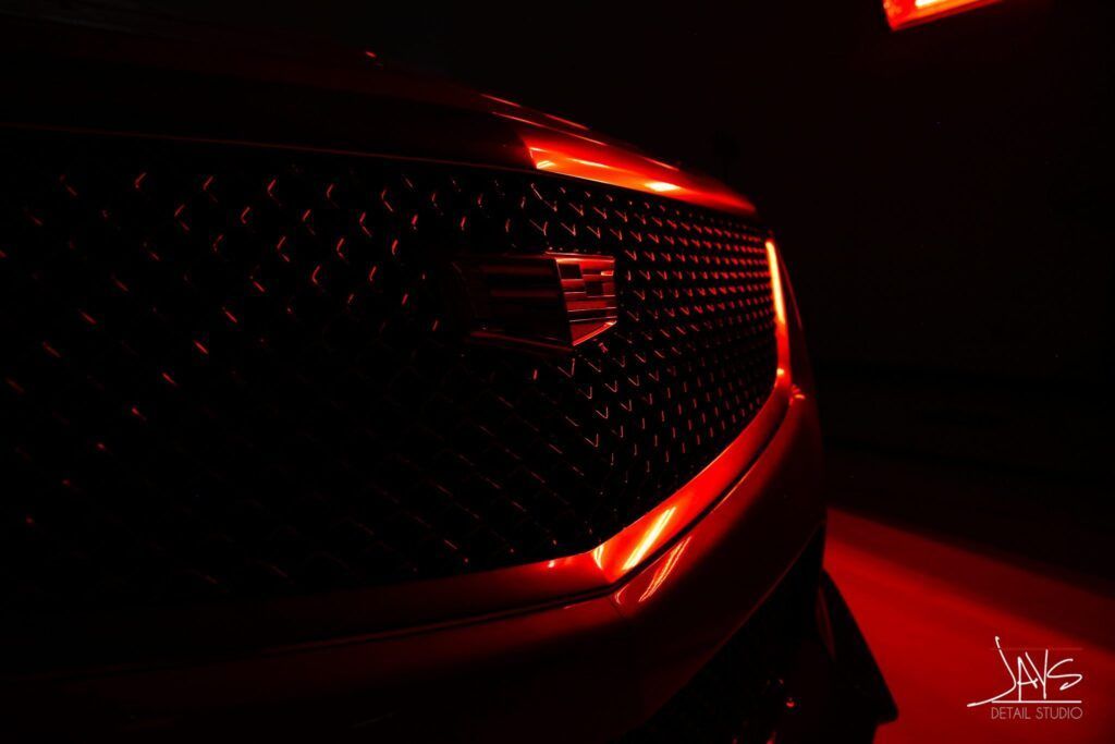 Close-up of a car grill glowing red in the dark.