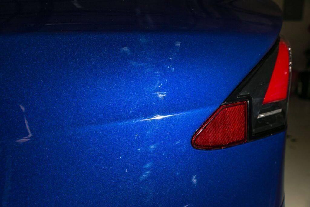 Blue car's rear with bird droppings and a red taillight.