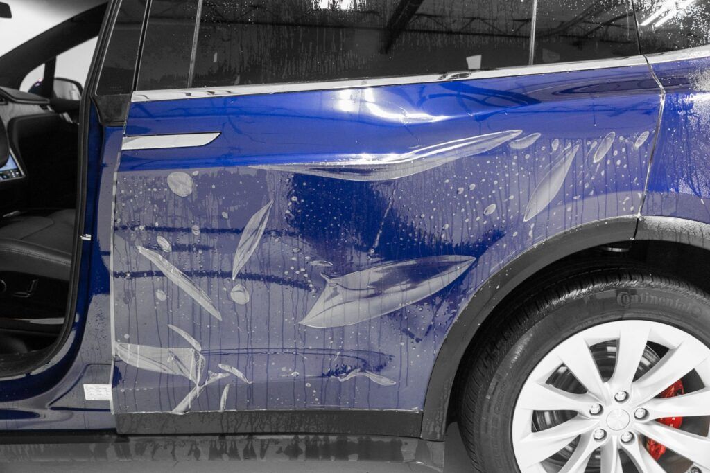Blue car door with clear protective film being applied.